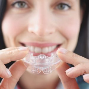 mujer-sonriente-sostiene-protector-bucal-plastico-transparente-enderezar-dientes